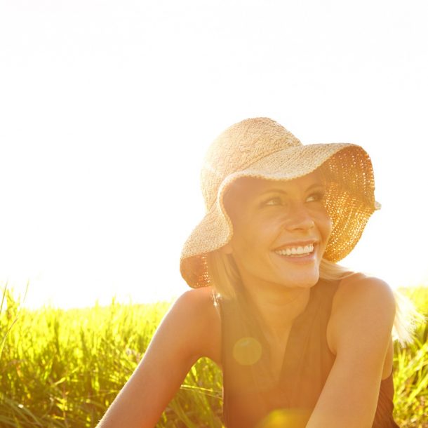 Young woman in a field with sun hat