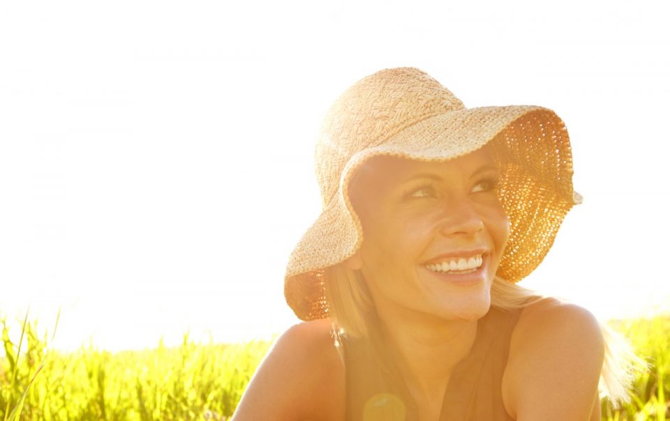 Young woman in a field with sun hat