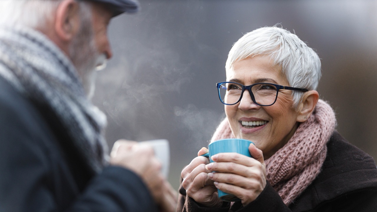 Old couple drinking hot drinks in cold weather