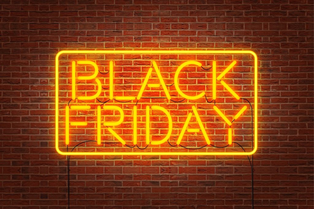 Black Friday neon lettering on a dark brick wall.